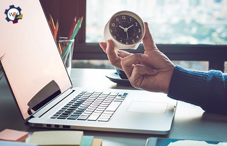 Mano Sosteniendo Reloj Frente a Laptop