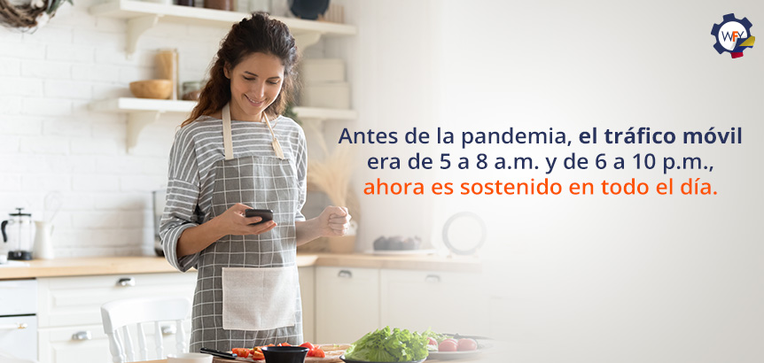 Mujer Sonriente Sosteniendo su Smartphone Mientras Prepara Comida en su Hogar